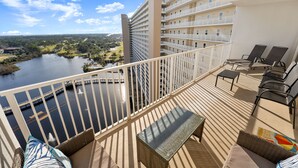 A balcony with a view of a river, a pool, and a building with multiple balconies.