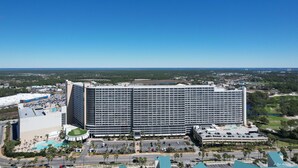 A large hotel with a central courtyard, multiple floors, and a parking area.