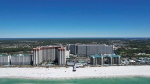 A coastal hotel complex with multiple high-rise buildings, a beachfront, and a clear blue sky.