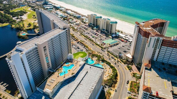 A high-rise hotel with a rooftop pool, a beach view, and a marina.
