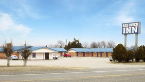 Red River Inn, con un grande cartello, un parcheggio e un edificio dal tetto blu.