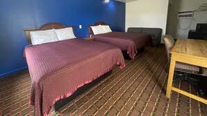 Una camera d'albergo con due letti, un divano, un tavolo e un condizionatore d'aria.