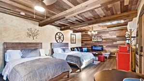 Ein Schlafzimmer mit zwei Betten, Holzbalkendecke, einem Fernseher und einem roten Kühlschrank.