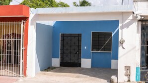 A small, single-story building with a blue and white facade, a black metal gate, and a small window. - Casa 66 (Mérida)
