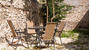 An outdoor dining area with a stone wall, a table, and four chairs. - Casa 66 (Mérida)