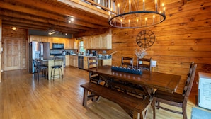 A spacious kitchen with wooden cabinets, a dining area with a large wooden table, and a ceiling with exposed beams and a chandelier. - Carolina Lookout - 10 mins to downtown Boone, hot tub, ping pong, long mountain views (Boone)