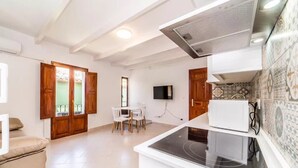 A modern kitchen with a built-in stove, a dining area with a table and chairs, and a TV mounted on the wall. - Alojamientos la Vila Mayor 7 (Villajoyosa)
