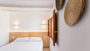 A bedroom with a wooden headboard, a bed with white bedding, and wall-mounted lights. - Alojamientos la Vila Mayor 7 (Villajoyosa)