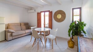 A living room with a sofa, dining table, chairs, a potted plant, and a large mirror on the wall. - Alojamientos la Vila Mayor 7 (Villajoyosa)