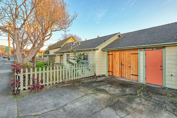 A residential property with a garage, a fenced yard, and a tree.