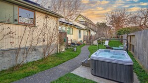 Ein Wohnhausgarten mit Whirlpool, einer Holzterrasse und einem Weg.