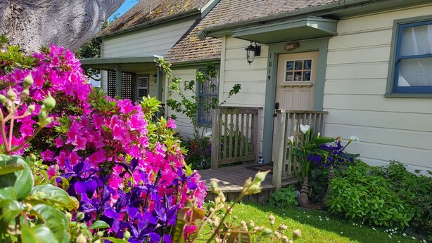 Ein Haus mit Veranda, Briefkasten und einem kleinen Garten mit Blumen.