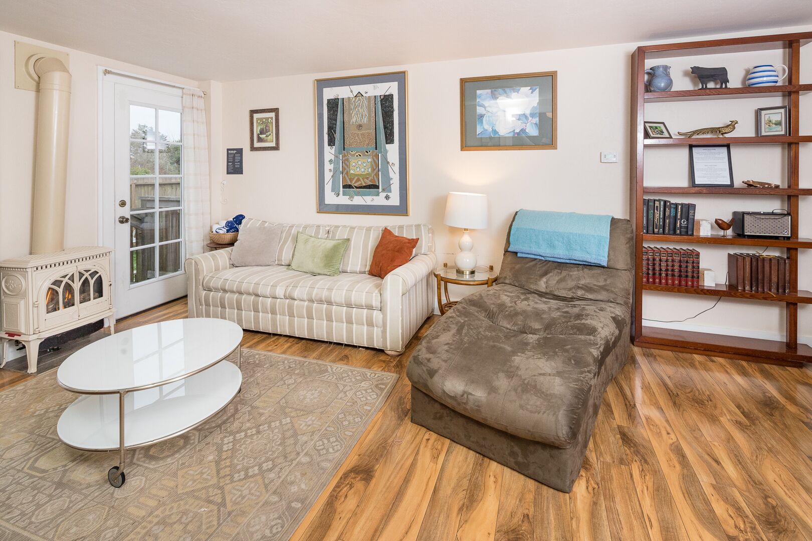 A cozy living room with a sofa, a loveseat, a coffee table, a fireplace, and a bookshelf.