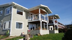 Ein zweistöckiges Haus mit Balkon, überdachter Veranda und kleinem Garten.