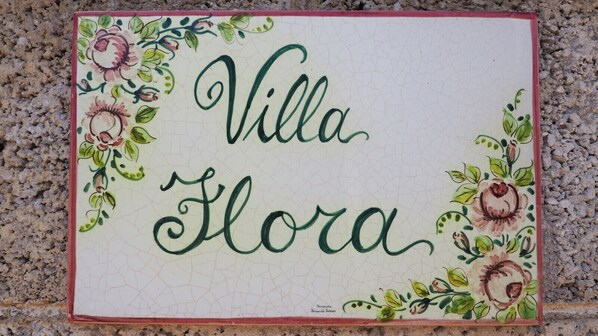 Ein Schild mit dem Schriftzug "Villa Flora", umgeben von floralen Mustern.