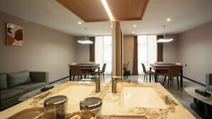 Una sala de estar moderna con comedor, un sofá, una mesa baja y una gran mesa de mármol.