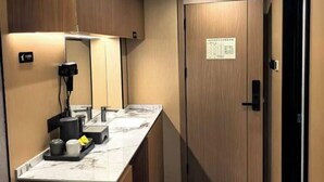 Un baño de hotel con encimera de mármol, lavabo, espejo y puerta de madera.