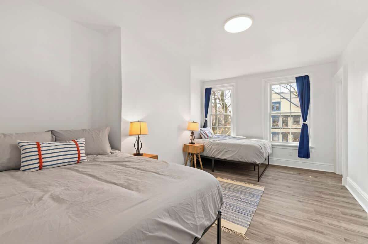 Ein Schlafzimmer mit zwei Betten, einem Fenster mit Vorhängen und Holzboden.