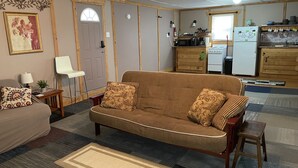 Una sala de estar con un sofá, una mesita con una lámpara, una silla y una alfombra.