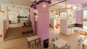 A modern interior with a herringbone-patterned floor, a purple accent wall, and a kitchen area with a white countertop and orange chairs. - LivinnX Barranquilla 1 (Puerto Colombia)