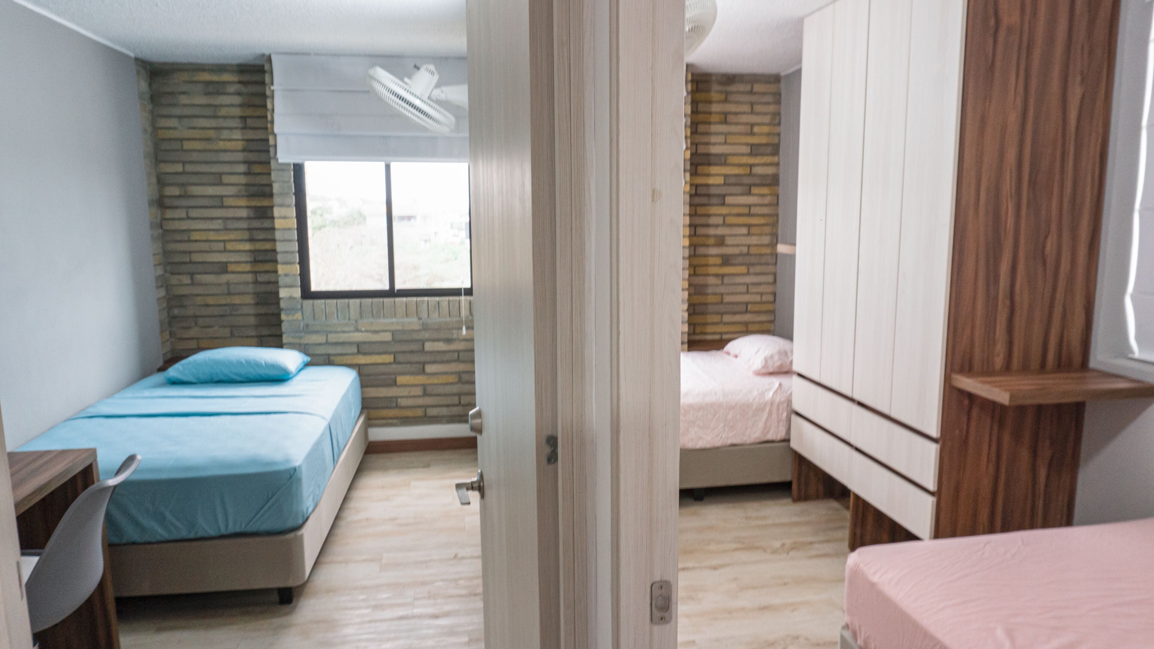 Ein Zimmer mit zwei Betten, einem Schreibtisch und einem Fenster.