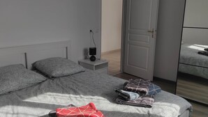 A bedroom with a bed, pillows, a bedside table with a lamp, and a wardrobe.