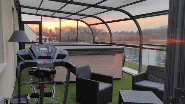 A covered outdoor area with a treadmill, seating, and a view of the sunset.