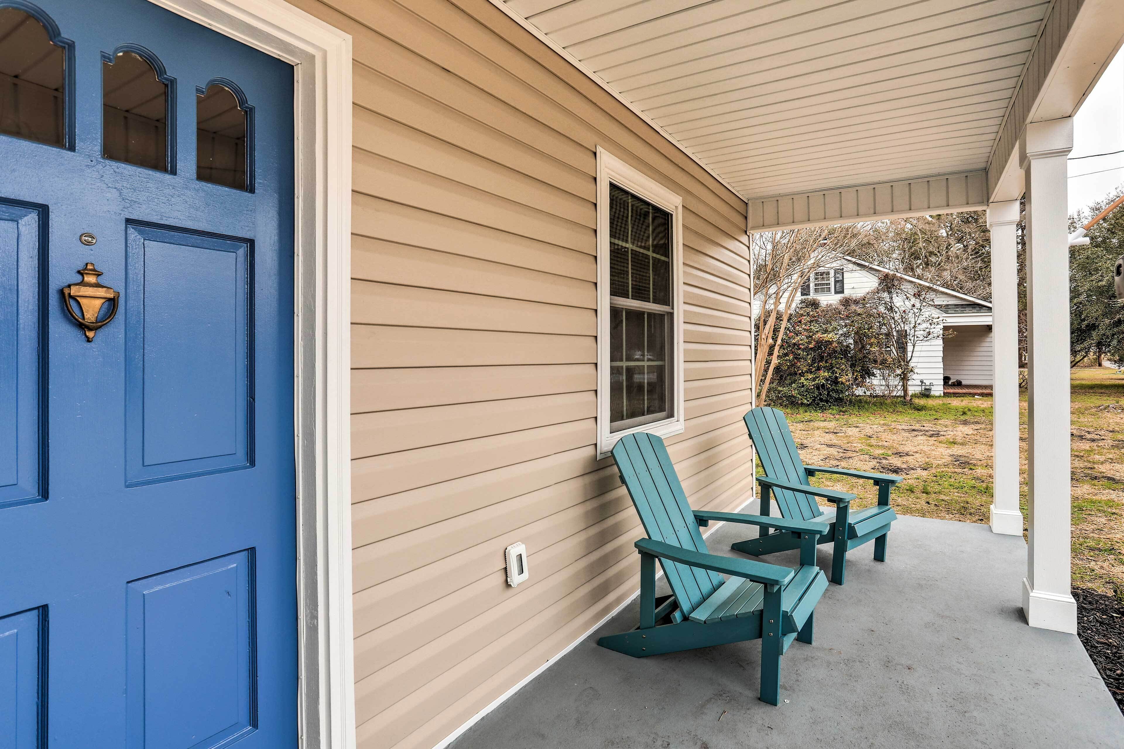 A porch with two Adirondack chairs and a blue door.
