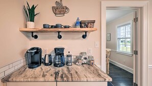 A kitchen with a marble countertop, coffee makers, jars, and a shelf with mugs and snacks. - New Bern Retreat w/ Fire Pit ~ 1 Mi to Dtwn! (New Bern)