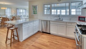 Une cuisine moderne avec des meubles blancs, un four encastré et un grand îlot central doté de tabourets.