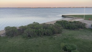 Une vue sur la côte, avec une zone herbeuse, une jetée et une mer calme.