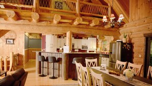Un ampio interno di una baita in legno, con zona pranzo, cucina e bancone.