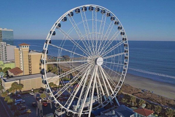 A large Ferris wheel with cabins, a beach, and buildings in the background. - HS-1205 12th Fl Oceanfront | Amazing Sunrise Views (Myrtle Beach)