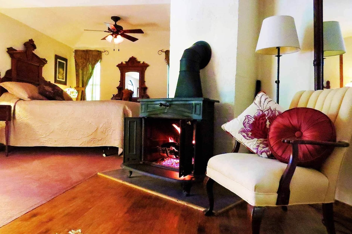 A cozy room with a fireplace, a bed, a chair, and a lamp.
