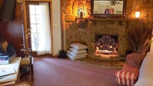 A cozy living room with a stone fireplace, a sofa, and a television.