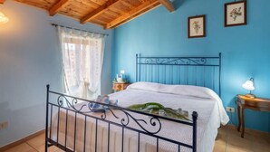Una camera da letto con soffitto in legno, un letto con testiera in metallo, un comodino e due quadri appesi al muro.