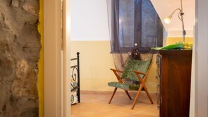 A room with a chair, a wooden cabinet, a window with a sheer curtain, and a lamp. - Apartment Giallo by Interhome (Vasia)