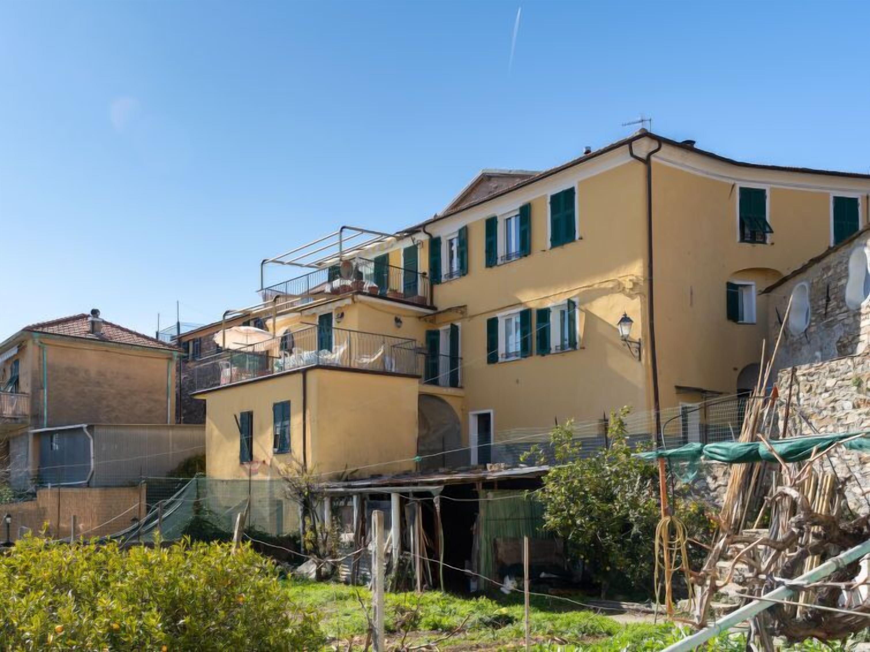 Un immeuble à plusieurs étages doté de balcons et d’un jardin situé à l’avant.