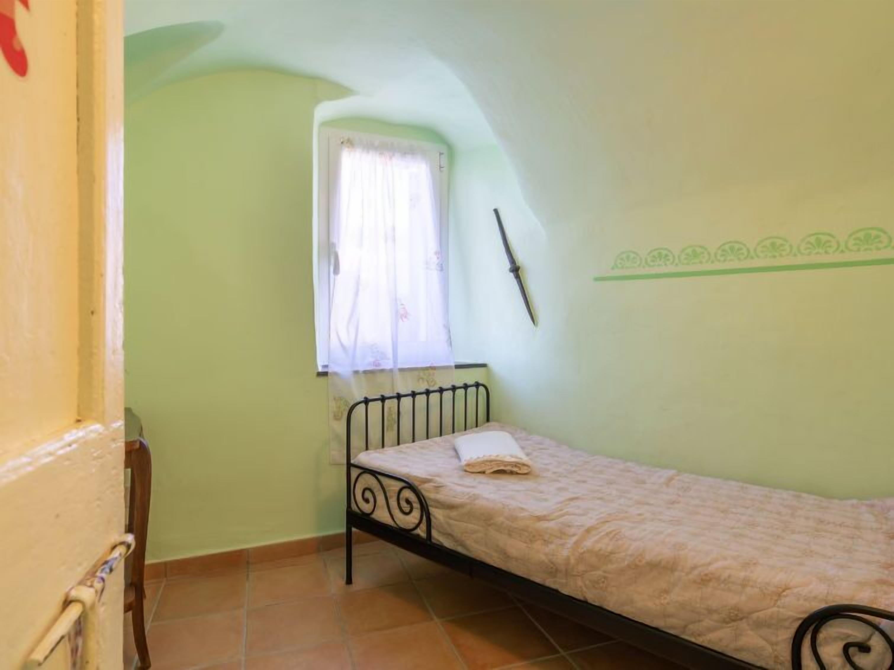 A small, single-bed room with a window and a radiator.