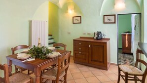 A dining area with a wooden table set for four, a wooden cabinet, and a tiled floor. - Apartment Verde by Interhome (Vasia)