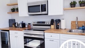A modern kitchen with white cabinetry, a stainless steel microwave, a gas stove, and a dishwasher. - South Sunrise Studio - Retreat in Forks (Forks)