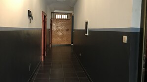 Un couloir aux murs noirs et blancs, doté d’un sol carrelé et d’une porte avec une fenêtre au bout.