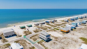 An aerial view of a coastal area with multiple buildings, roads, and a beach.