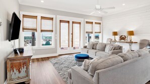 A living room with a sofa, ottoman, and a television on a cabinet.