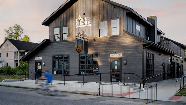 A building with a sign reading "Barn Burner Events, Lodging & More" and a "Service" door. - Barn Burner: Luxe 9BR for 29 ppl in Downtown Nashville, IN (Nashville)