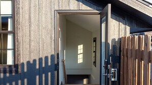 A modern building with a wooden exterior, a glass door entrance, and a visible staircase leading inside. - Barn Burner: Luxe 9BR for 29 ppl in Downtown Nashville, IN (Nashville)