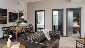 A modern living room with a leather sofa, a dining table with chairs, and a chandelier. - Barn Burner: Luxe 9BR for 29 ppl in Downtown Nashville, IN (Nashville)