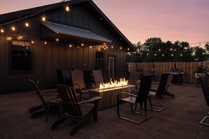 An outdoor patio with a fire feature, seating, and string lights. - Barn Burner: Luxe 9BR for 29 ppl in Downtown Nashville, IN (Nashville)