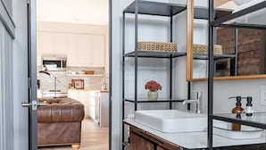 A modern bathroom with a wooden vanity, a large mirror, and a built-in shelf unit. - Barn Burner: Luxe 9BR for 29 ppl in Downtown Nashville, IN (Nashville)