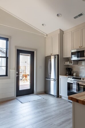 A modern kitchen with stainless steel appliances, a black-framed door, and a view to the outside. - Barn Burner: Luxe 9BR for 29 ppl in Downtown Nashville, IN (Nashville)